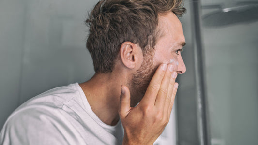 Man applying redness primer skincare in front of a mirror